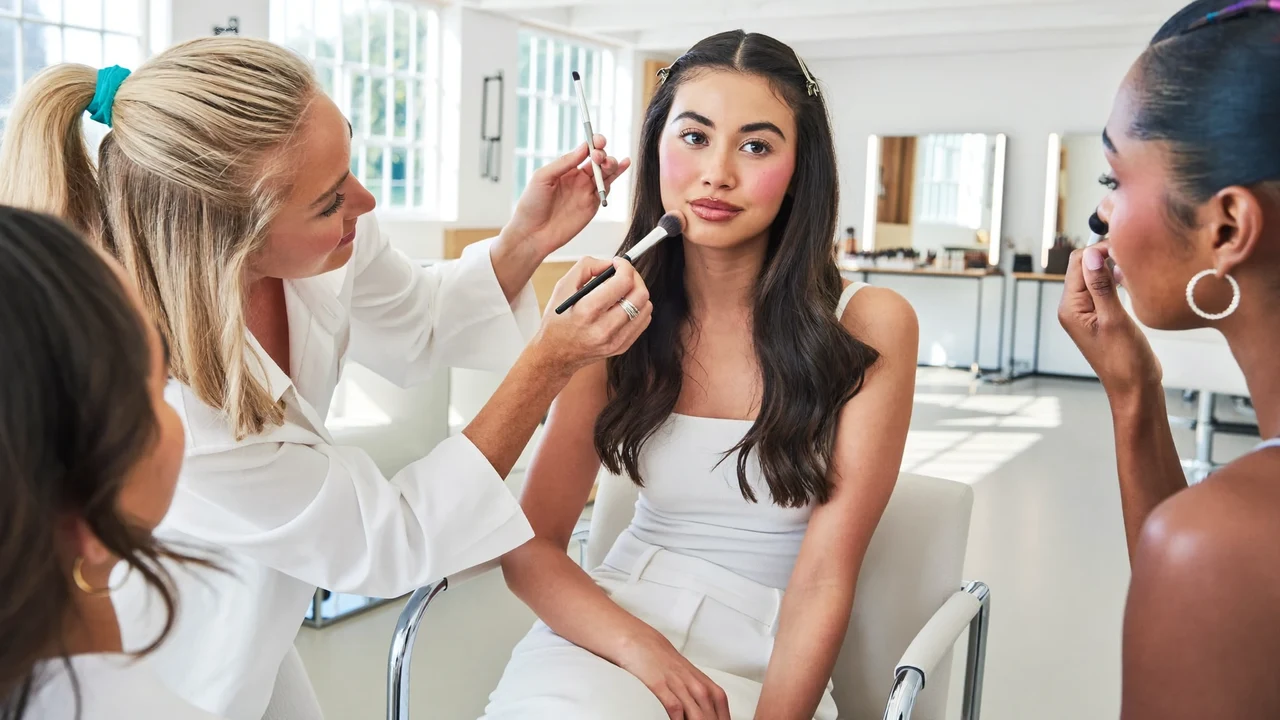 Lyst makeupstudie med model, underviser og to elever ved spejlet